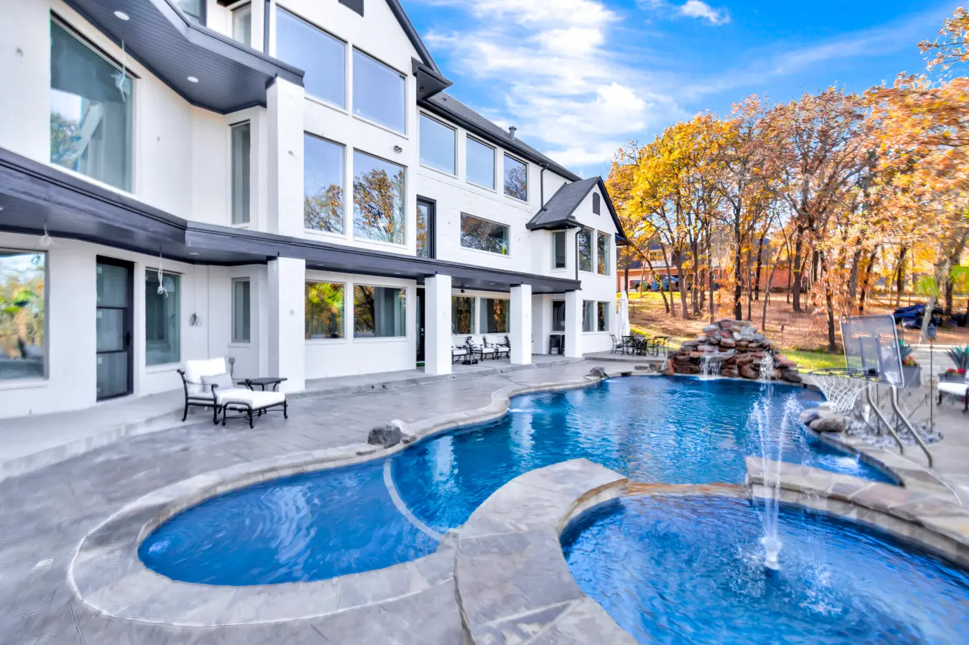 Freeform pool with fountain jets below the tiered balconies of a white painted home