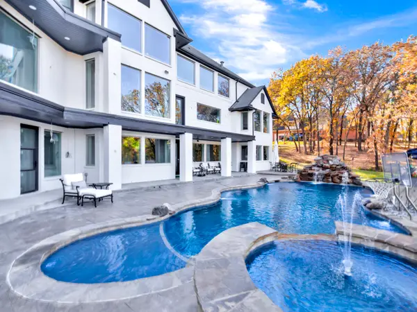 Freeform pool with fountain jets below the tiered balconies of a white painted home