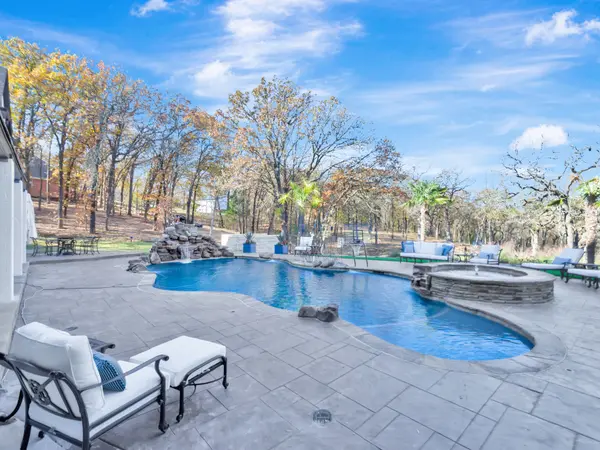 Pool terrace looking out to woodland, with a rock waterfall and raised spa