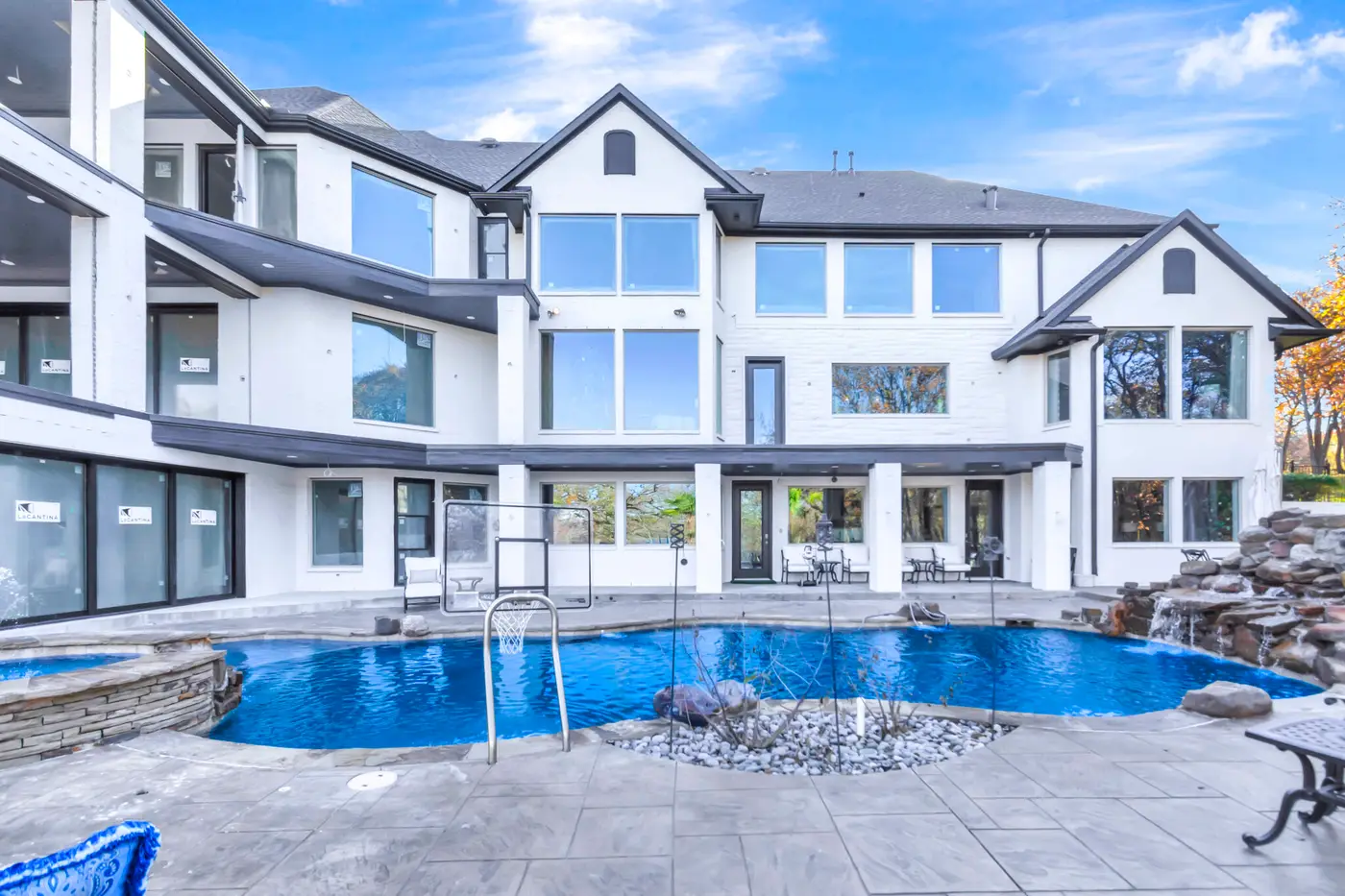 Rear elevation with painted gables and tall windows above a pool and rock waterfall