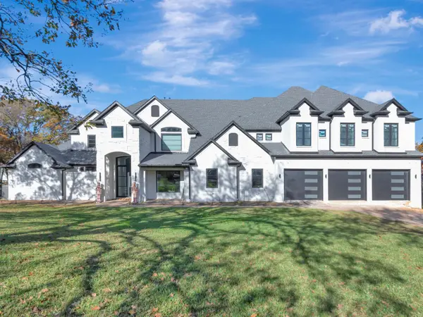 Front elevation of a painted brick and stone house with three dark garage doors and dormer windows