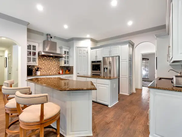 Kitchen with white painted cabinetry, a peninsula bar and granite countertops